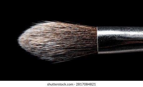 Macro shot of a makeup brush with soft bristles isolated on a black background.