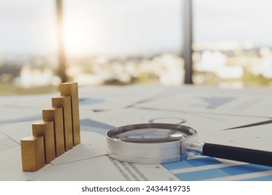 Magnifying glass and gold bar graph growing on the documents that show Earnings graph Placed on the table in the conference room, ideas, planning, business growth. - Powered by Shutterstock