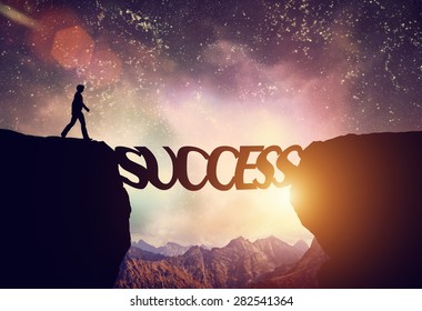 Man about to walk over precipice on SUCCESS word bridge. Dream sky and mountains. Motivation, ambition, business concept. - Powered by Shutterstock