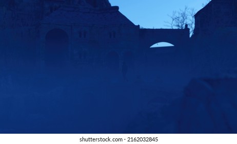 Man In Hoodie Walks On A Bridge Of An Ancient Misty Castle At Dusk. 3D Render.