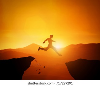 Man jumping from one rock to another. Sunset mountains scenery. Risky challange, winning, brave decision concept.