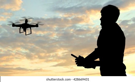 man operating of flying drone quadrocopter at sunset
