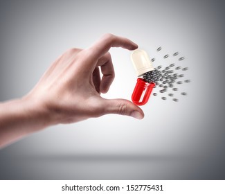 Man's Hand Holding Large Capsule And Small Nano Balls