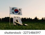 Memorial Day concept background with a tiny Korean flag tucked between a row of nameless soldiers and fallen shell casings. 3d rendering
