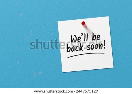 The message we will be back soon written on a note paper pinned on a blue concrete wall. 3D rendering.