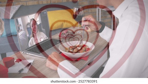 Middle-aged man dining, toasting wine to young girlfriend on laptop. Caucasian couple enjoying virtual dinner date with a red background - Powered by Shutterstock