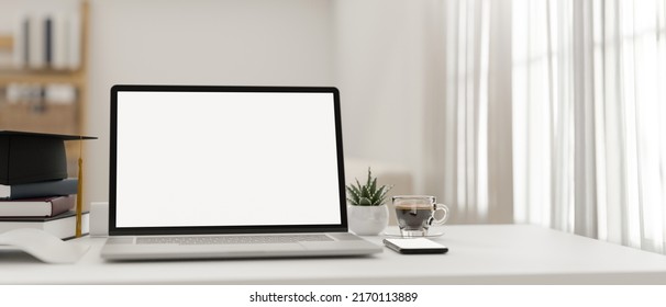 Minimal White Bright Home Workspace With Notebook Laptop Computer Blank Screen Mockup, Book, Coffee Cup, Smartphone And Graduation Cap. 3d Rendering, 3d Illustration