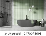 Modern bathroom with freestanding dark bathtub, green tiled wall background, and minimalist design. Concept of simple and serene interior.  3D Rendering