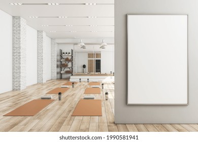 Modern Concrete Yoga Gym Interior With Equipment, Blank Banner On Wall, Daylight And Wooden Flooring. Healthy Lifestyle Concept. Mock Up, 3D Rendering