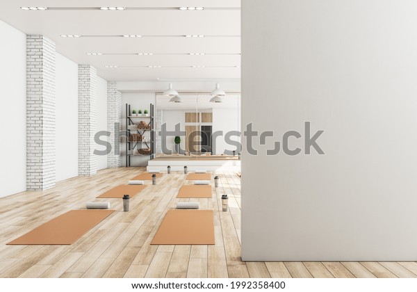 Modern concrete yoga gym interior with\
equipment, blank mockup space on wall, daylight and wooden\
flooring. Healthy lifestyle concept. Mock up, 3D\
Rendering