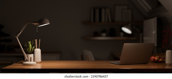Modern dark wooden office desk at night under the warm light from table lamp with laptop computer, accessories and copy space for product display. close-up. 3d rendering, 3d illustration