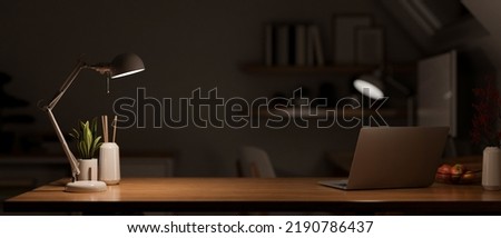Modern dark wooden office desk at night under the warm light from table lamp with laptop computer, accessories and copy space for product display. close-up. 3d rendering, 3d illustration 商業照片 © 
