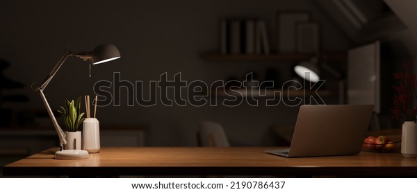 Modern\
dark wooden office desk at night under the warm light from table\
lamp with laptop computer, accessories and copy space for product\
display. close-up. 3d rendering, 3d\
illustration