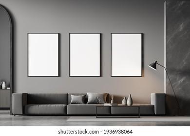 Modern living room interior with arch and three white poster on dark wall. Grey sofa with cushions, coffee table, chest of drawers and lamp. Concrete floor. 3D rendering