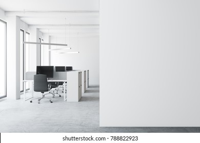 Modern Open Space Office Environment With A Concrete Floor, Tall Windows, And Cubicles With Computer Tables. A White Wall Fragment. 3d Rendering Mock Up