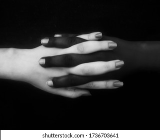 Monochromatic photo for two black & white hands with different positions showing unity, harmony, integration, and acceptance fighting against racism,prejudice, discrimination, racialism and xenophobia