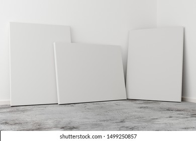Multiple empty picture frames canvases leaning against white wall in bright room with grey concrete floor with copy space - portfolio, gallery or artwork template mock up - 3D illustration