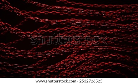 Multiple red chains lay on top of a black background. The chains are out of focus, and the red color gives the image a dark, sinister feel.