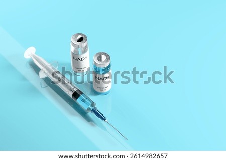 NAD solution in vials for injection and syringe on a blue glossy laboratory table. Concept of anti-aging therapy and life extension. 3d illustration, rendering. Copy space