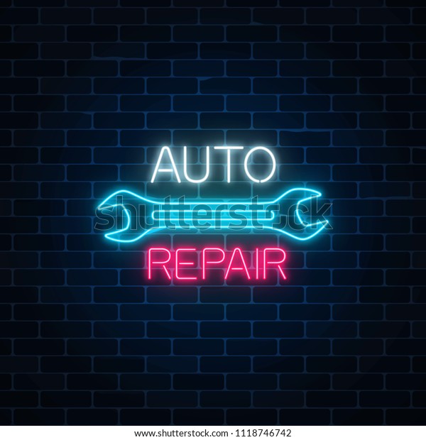 Neon auto repair shop sign on dark\
brick wall background. Glowing night advertising\
symbol.