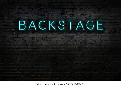 Neon sign on brick wall at night. Inscription backstage