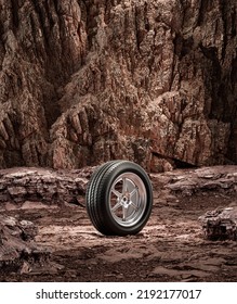 A New Car Wheel Standing On A Rocky Stage. A Car Tire Standing Upright And Sideways On Rocky Ground In Front Of A Natural Cliff. 3d Rendering, No People