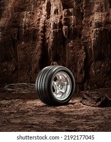 A New Car Wheel Standing On A Rocky Stage. A Car Tire Standing Upright And Sideways On Rocky Ground In Front Of A Natural Cliff. 3d Rendering, No People