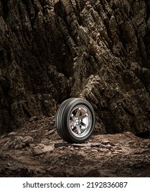 A New Car Wheel Standing On A Rocky Stage. A Car Tire Standing Upright And Sideways On Rocky Ground In Front Of A Natural Cliff. 3d Rendering, No People