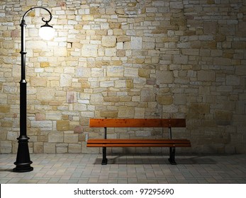 Night View Of The Illuminated Brick Wall With Old Fashioned Street Light And Bench