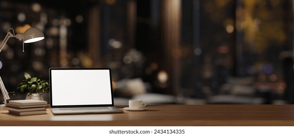 An office desk workspace in a modern dark office room at night features a white-screen laptop computer mockup, dim light from a table lamp, and decor. 3d render, 3d illustration - Powered by Shutterstock