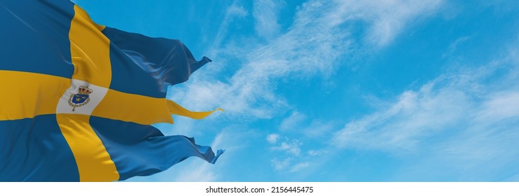 official flag of Sweden Royal flag lesser coa , Sweden at cloudy sky background on sunset, panoramic view. Swedish travel and patriot concept. copy space for wide banner. 3d illustration