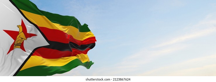 official flag of Zimbabwe at cloudy sky background on sunset, panoramic view. patriot and travel concept. copy space for wide banner. 3d illustration