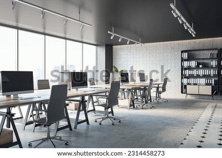 Open office interior with desks, computers, a concrete floor, and black ceiling. A window provides natural light. Modern workspace design and business background. 3D Rendering