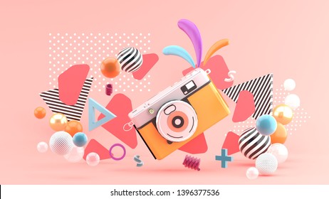 Orange camera surrounded by graphics and colorful balls on a pink background.-3d rendering.