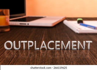 Outplacement - letters on wooden desk with laptop computer and a notebook. 3d render illustration.