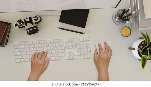 Overhead shot, A female hands typing on computer keyboard on a modern office workspace with camera, stationery, office supplies and decor on white table background. 3d rendering, 3d illustration