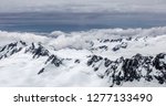 Panoramic view of snowy mountaintops under layers of clouds in Westland Tai Poutini National Park in the Southern Alps on the South Island of New Zealand, with digital oil-painting effect