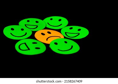 Paper Cutout Image Of Green Smiley Faces Surrounding A Sad Face. Concept Of Psychology, Therapy, Emotions, Mental Health, Circles Of Trust, Friendship And Family. Black Background. Selective Focus