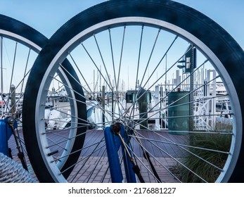 Partial view of river marina through wheels of bicycle parked upside down near dock on a summer morning in Stuart, Florida. Digital oil-painting effect, 3D rendering.