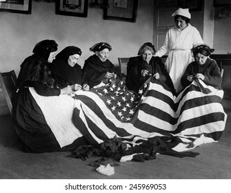 Patriotic Elderly Immigrant Women Making A Flag During WWI. They Are From Eastern Europe Countries Of Hungary, Galicia, Russia, Germany, And Rumania. Ca. 1918.