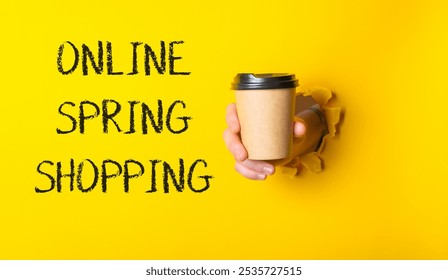 Person holding a coffee cup with the words online spring shopping written in black on a yellow background - Powered by Shutterstock