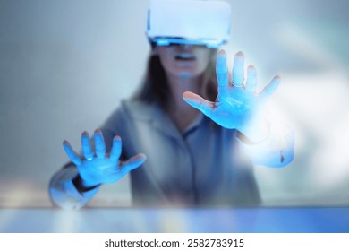 Person using VR headset, reaching out with hands. Immersive virtual reality experience. Blue light, futuristic technology. Engaged in VR, exploring digital space.