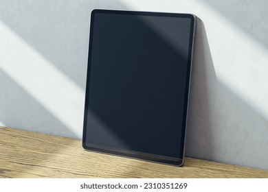 Perspective view on blank dark digital tablet screen with place for web site or design on wooden surface and sunlit light wall background, advertising and marketing concept. 3D rendering, mock up