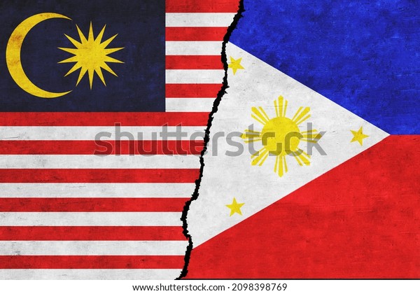 Philippines and Malaysia painted\
flags on a wall with a crack. Philippines and Malaysia conflict.\
Malaysia and Philippines flags together. Philippines vs\
Malaysia