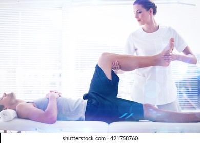 Physiotherapist massaging leg of man against lens flare