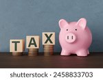 Pink piggy bank standing next to wooden toy blocks showing the word TAX on stacks of gold coins. 3D illustration of the concept of taxation, tariff, income tax and capital gain tax 