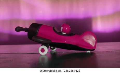 A pink toy airplane for girls with a pilot inside on a wooden table. The cosmic environment and the northern lights. The concept of aviation. 3D illustration - Powered by Shutterstock