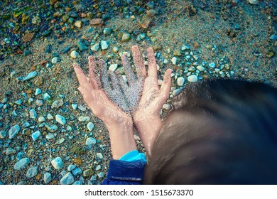 Plastic Effect Image of Back of the Head, Two Hands Together Partially Covered with Wet Coarse Sand, Pebbles in Background. Environment Problems Concept.
