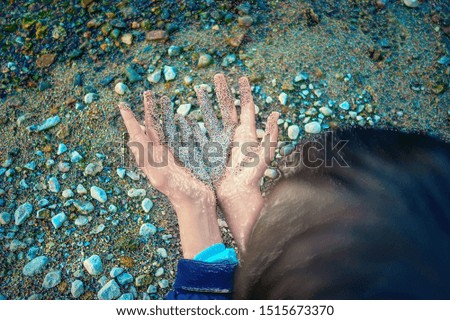Plastic Effect Image of Back of the Head, Two Hands Together Partially Covered with Wet Coarse Sand, Pebbles in Background. Environment Problems Concept.