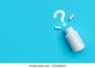 Plastic medical container and white capsule pills with question mark on blue background copy space top view. Medicine and health concept. 3d rendering.